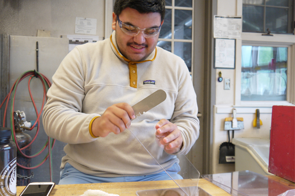 Student wearing safety goggles assembles a face shield