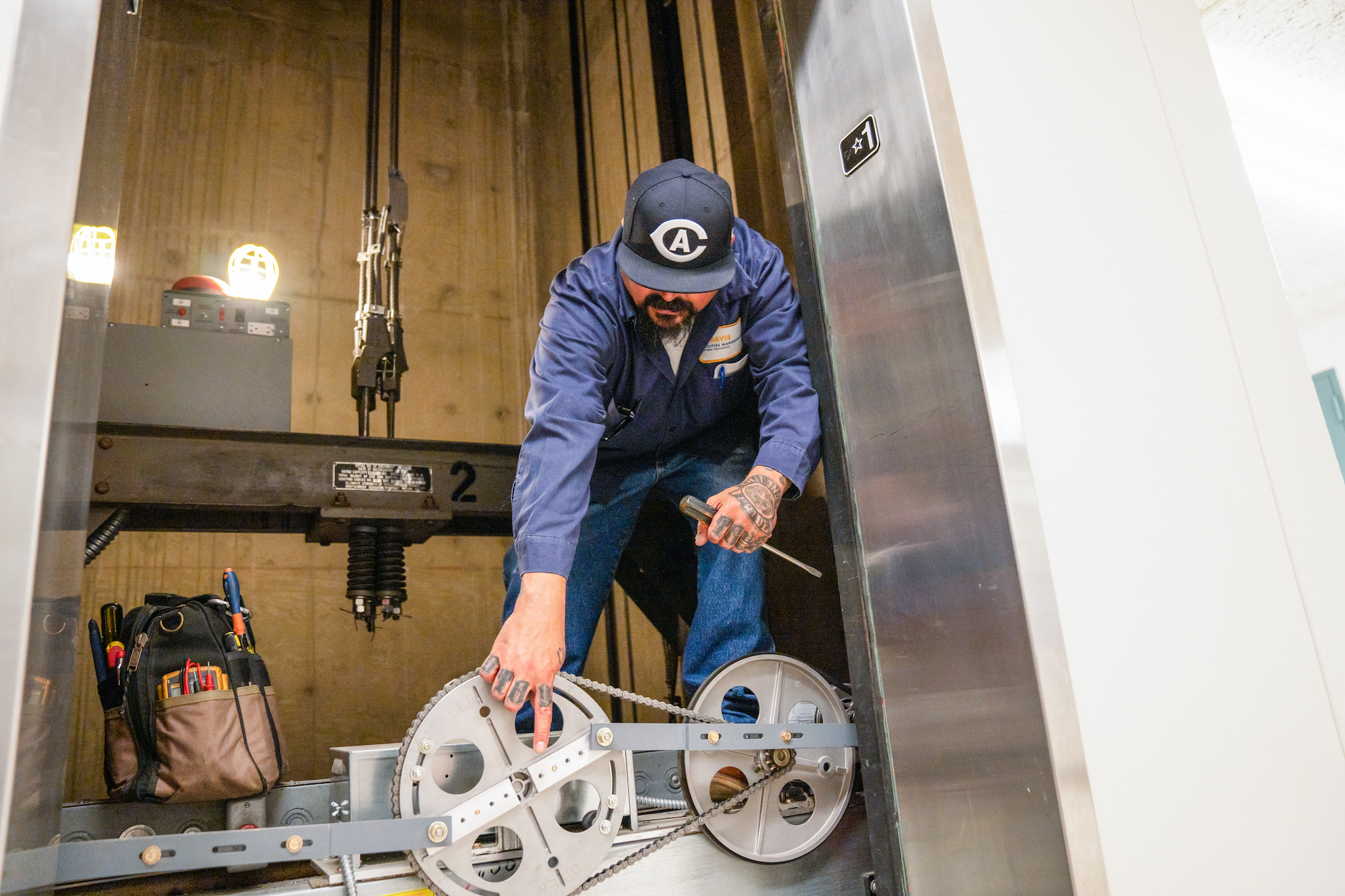 A Facilities Management staff member performs maintenance on an elevator