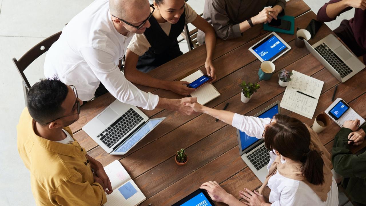 People gathered around a table with laptops and tablets