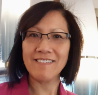 Smiling woman with glasses and short dark hair, soft indoor lighting