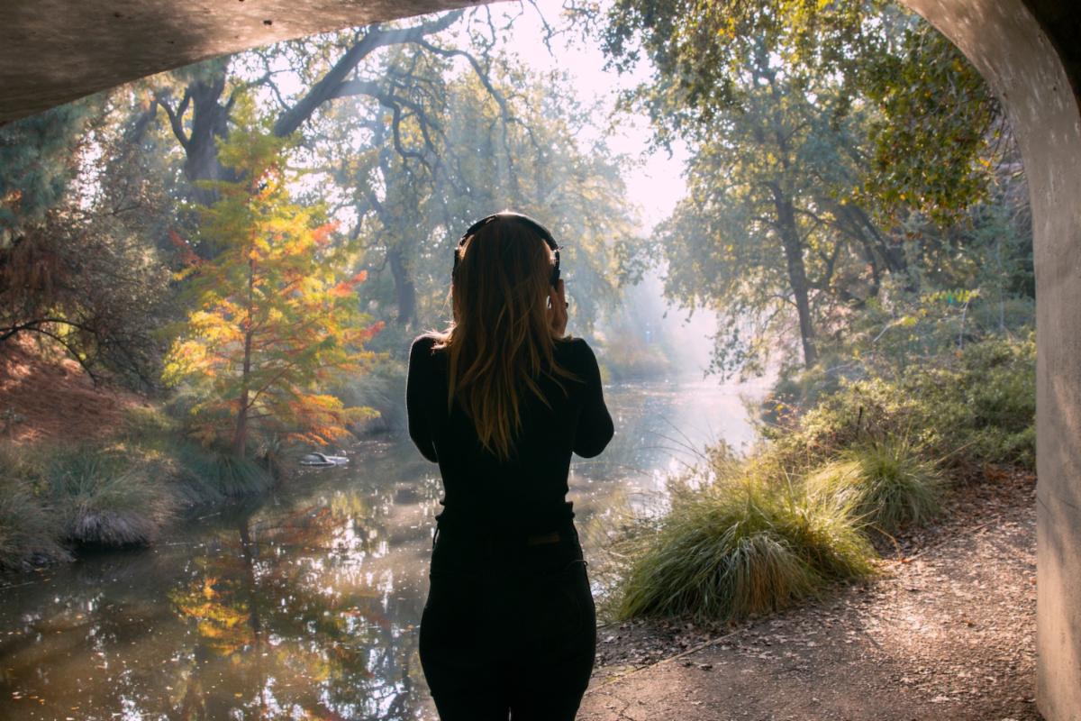 Person with headphones walking under a bridge, wearing headphones