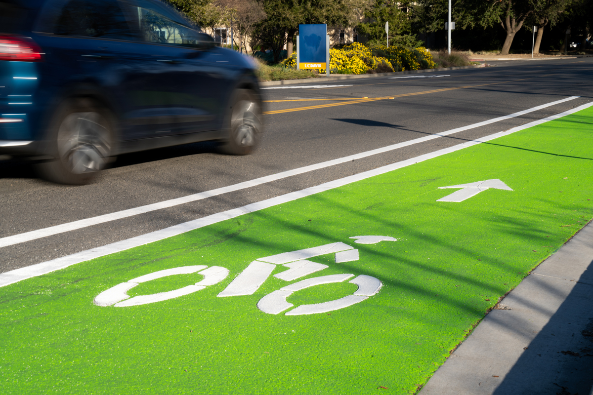 A car drives on La Rue Road alongside a bright green, freshly painted bike lane