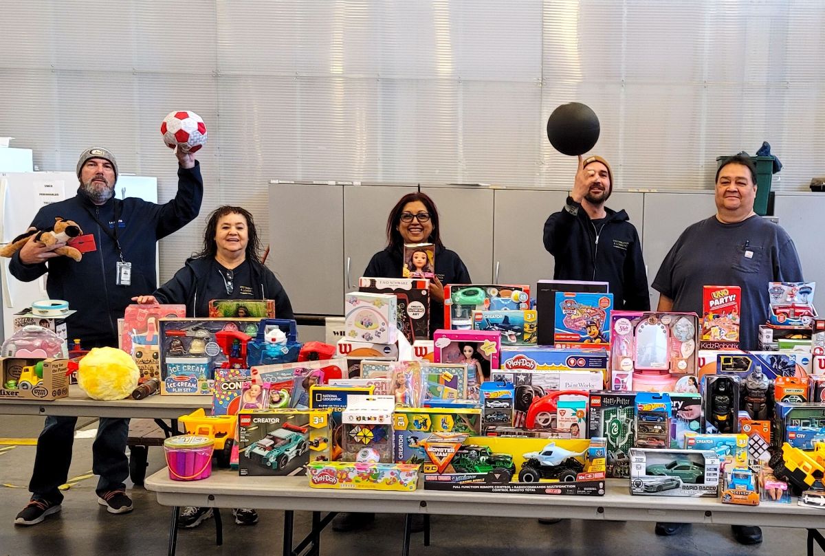 Mail Services employees pose behind tables full of toys