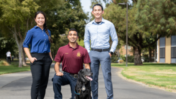 three offices in plainclothes on the UC Davis campus, one kneeling with dog