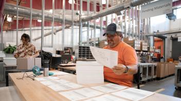 UC Davis employee sorts through a stack of papers by hand in a warehouse.