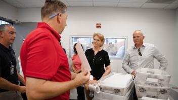 Employees talk amid US Postal Service mail bins