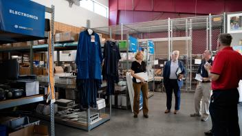 Group discussion inside a storage area with racks and aisle labels for Electronics and Lab Items