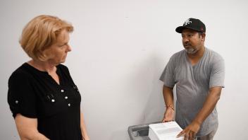 Shinnerl listens to mail coordinator while he works with a pile of documents