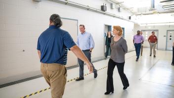 tour leader walks backwards in front of small group in hallway lined with hazard tape