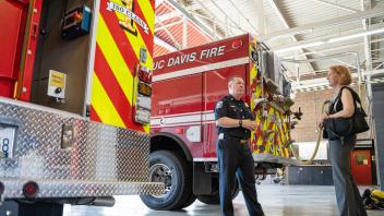 Behind emergency vehicles and fire trucks, fire chief and vice chancellor talk