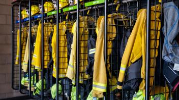 rack with firefighter equipment hanging in cubbies including protective coats and hats