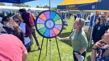 Staff member spins a prize wheel at the Safety Services table