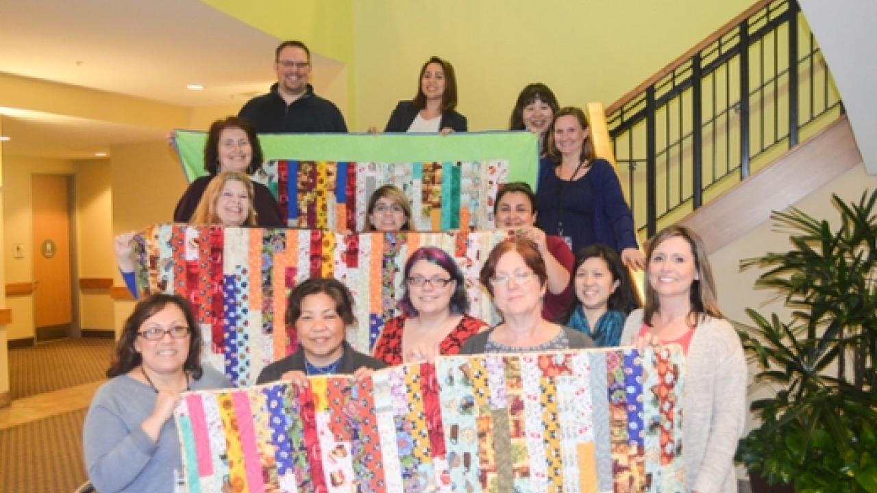 The three quilts being donated to the UC Davis Comprehensive Cancer Center. Photo of group with quilts