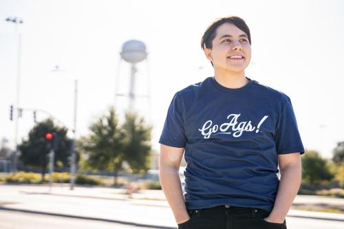 Employee wearing Go Ags! T-shirt with campus water tower in the background.