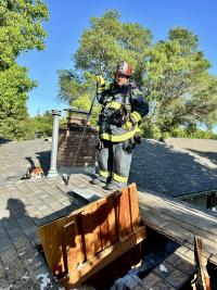 Steve Dunn in his firefighting gear stands on a roof.