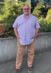 Randall Williams stands with his hands in his pockets and smiles at the camera.