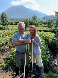 Sandy Batchelor and her husband Mark smile in front of a volcano in the distance.