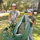 Two students holding up bags of yard waste.