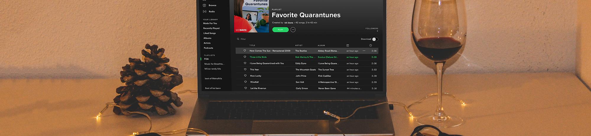 laptop on a desk showing spotify playlist called favorite quarantunes